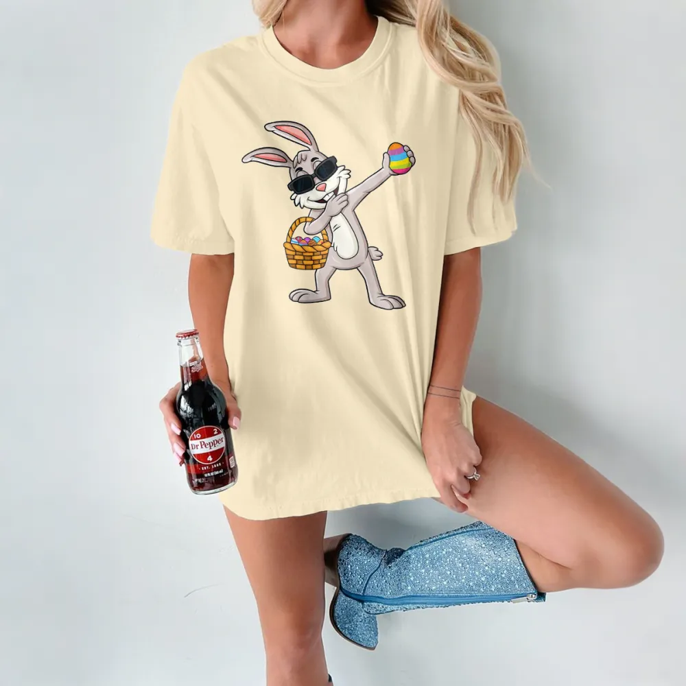 A Cartoon Rabbit Wearing Black Sunglasses, Holding A Colorful Easter Egg, With A Basket Full Of Eggs Next To The Other Hand. The Style Is Playful And Cute, With A Casual T-Shirt.